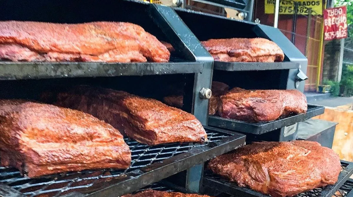 Costelas e peças de carne na grelha do defumador da casa