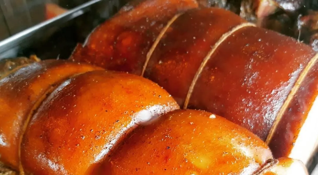 Peças de barriga suína assadas e douradas, amarradas com barbante